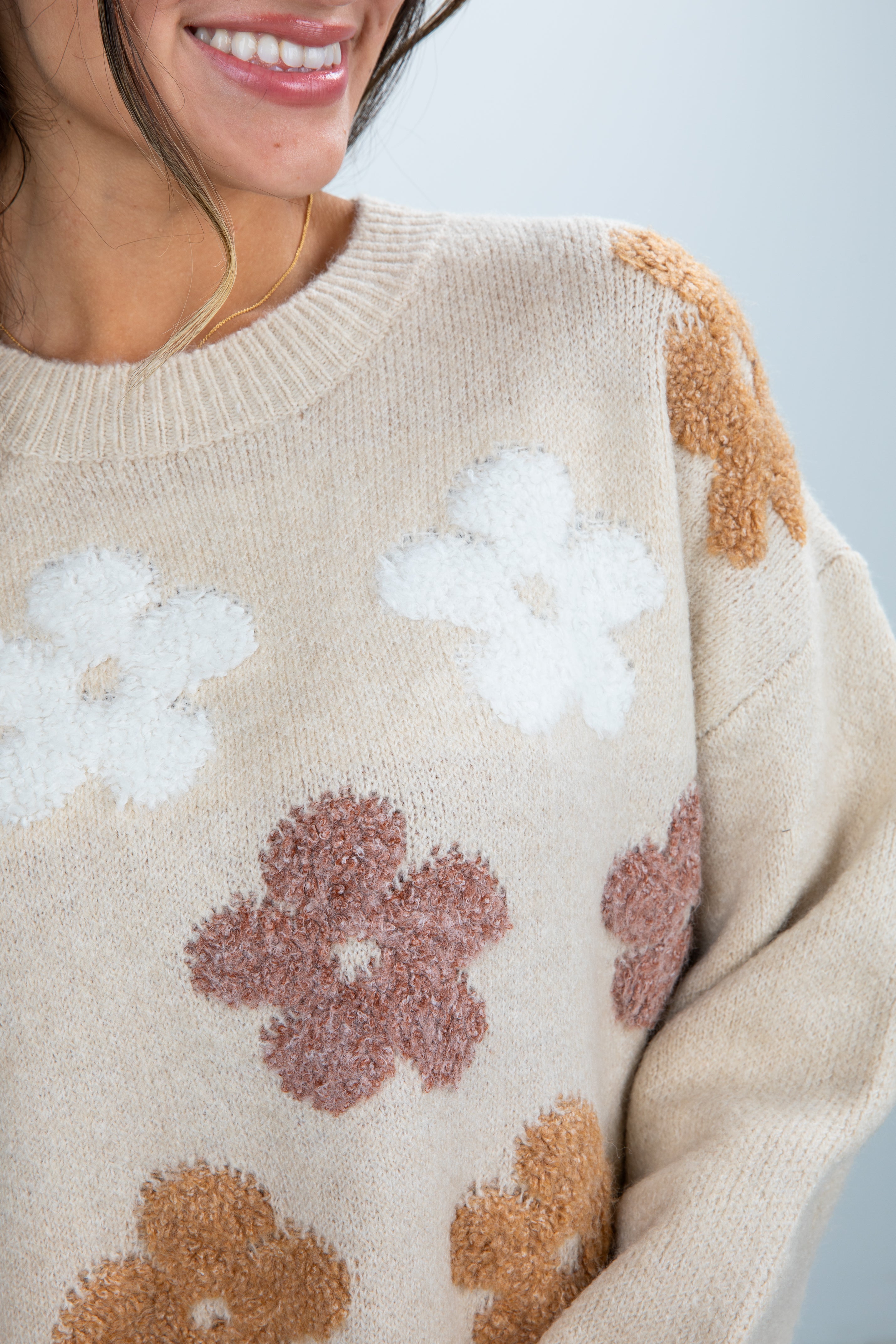 Beige sweater with floral patterns worn by a person