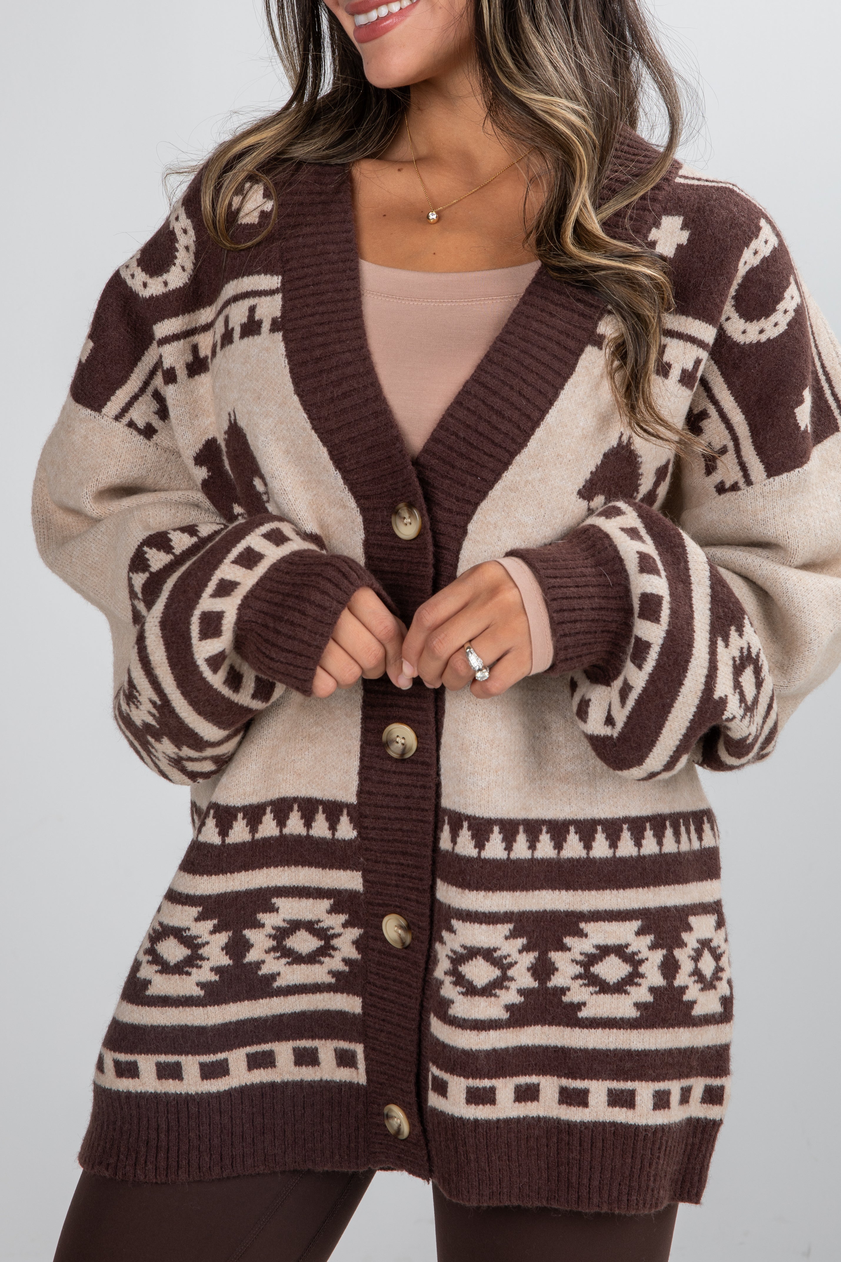 Person wearing a patterned cardigan with a neutral background