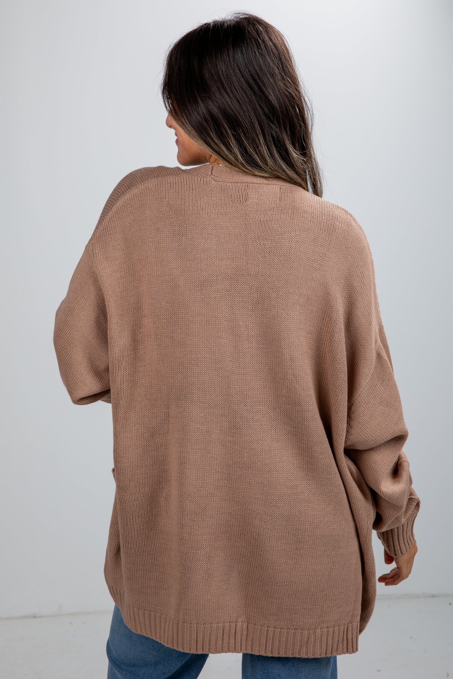 Person wearing a brown sweater against a white background