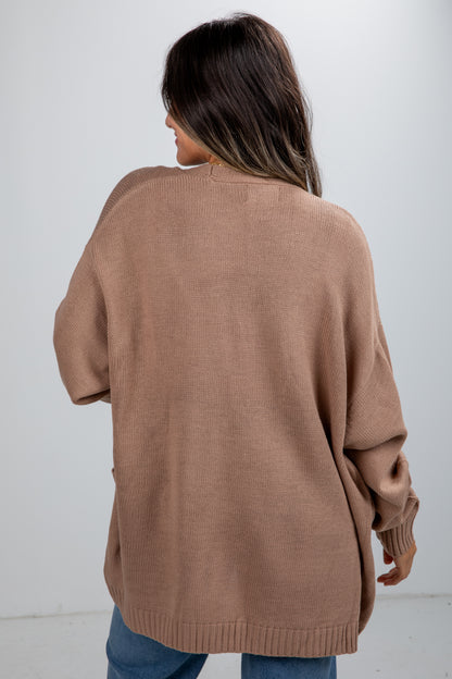 Person wearing a brown sweater against a white background