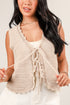 Woman wearing a beige knitted vest over a white top against a plain background