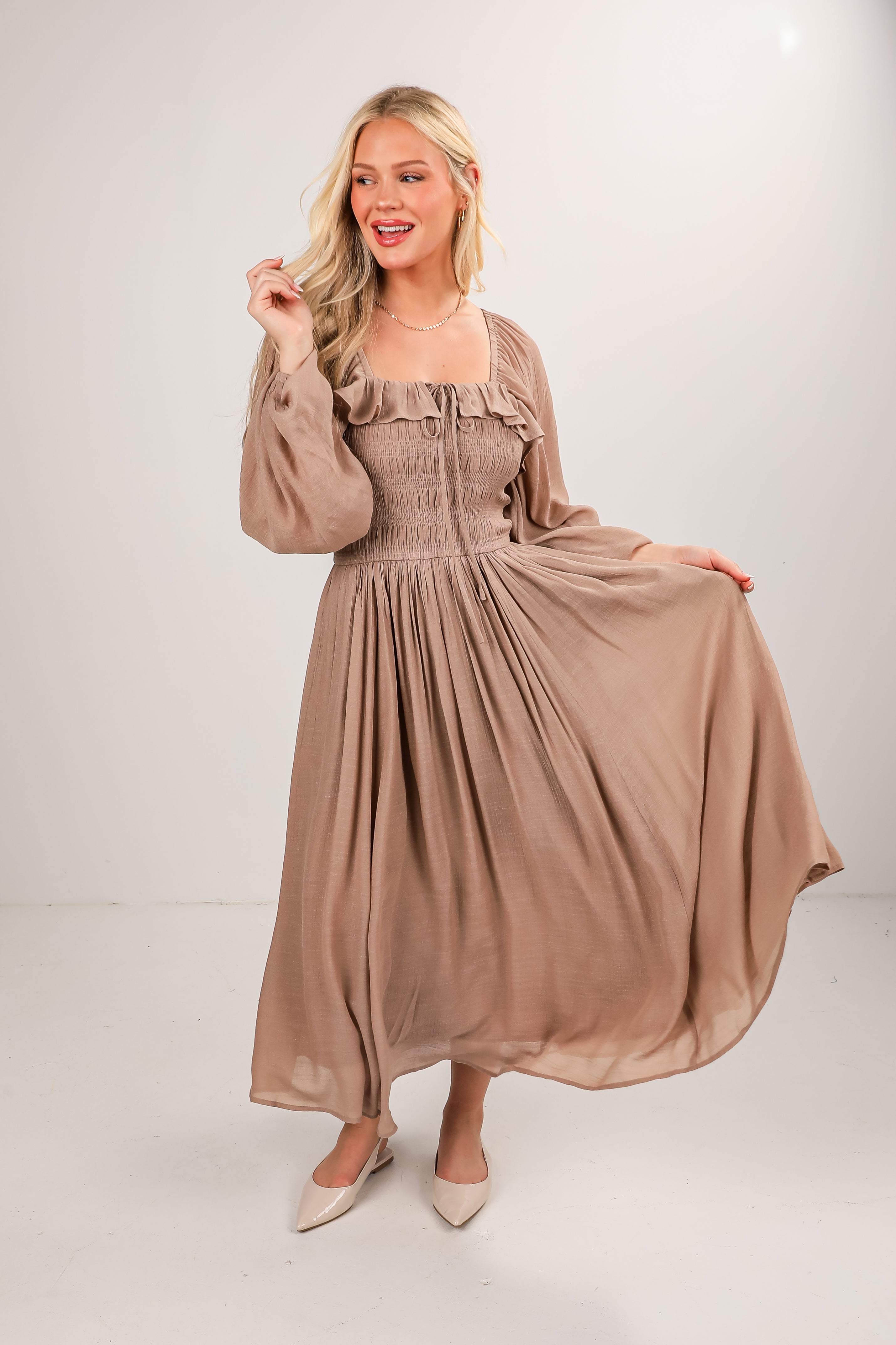 Woman wearing a long beige dress on a white background