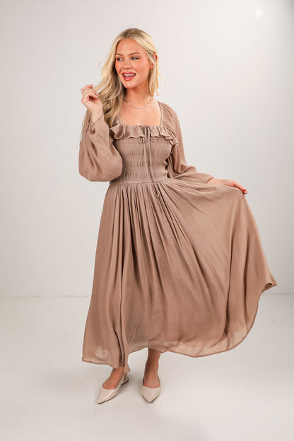 Woman wearing a long beige dress on a white background