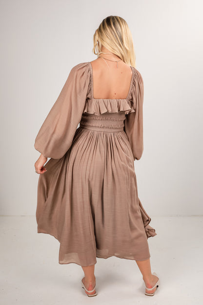 Woman wearing a beige dress with long sleeves on a white background