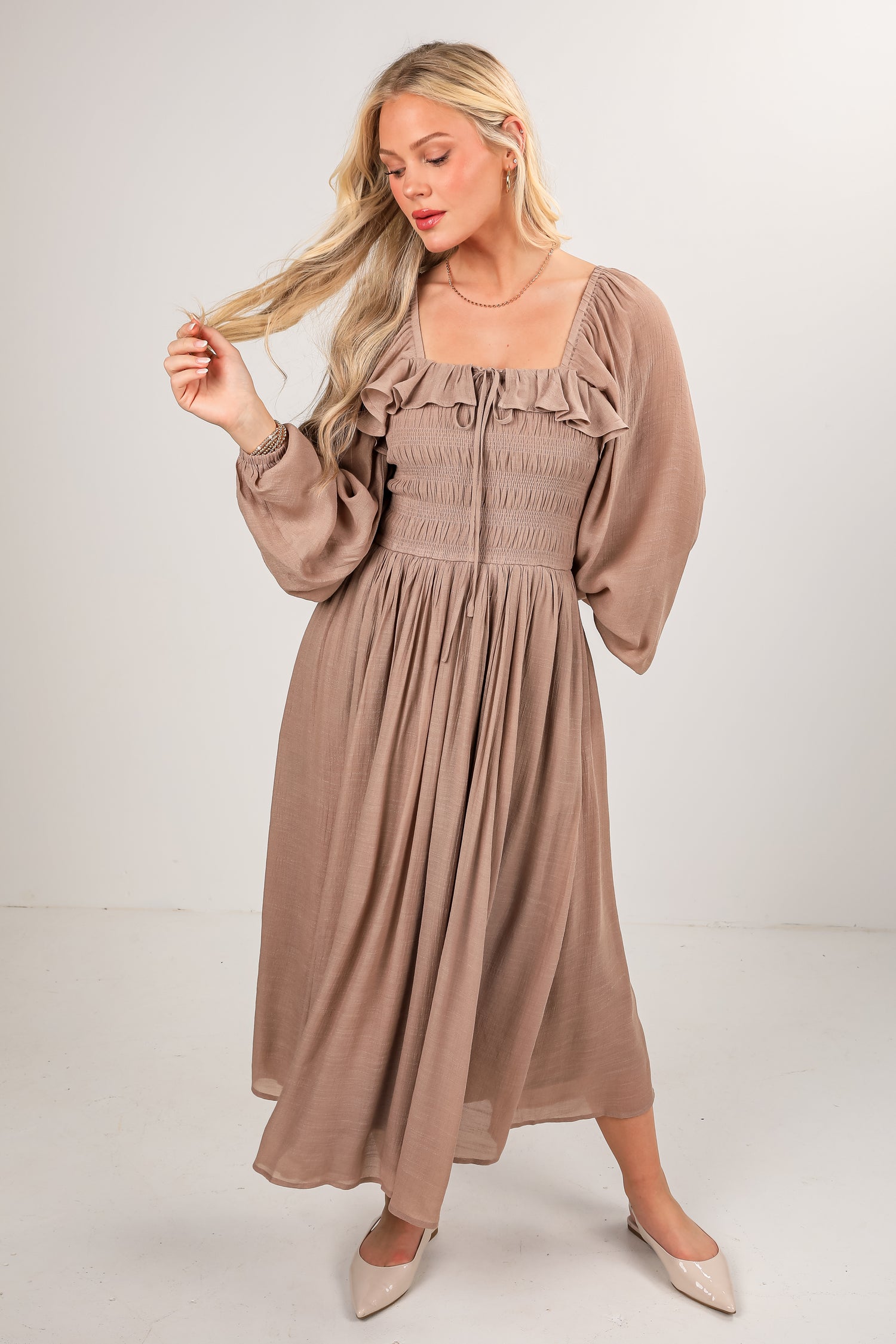 Woman wearing a brown dress with long sleeves on a white background