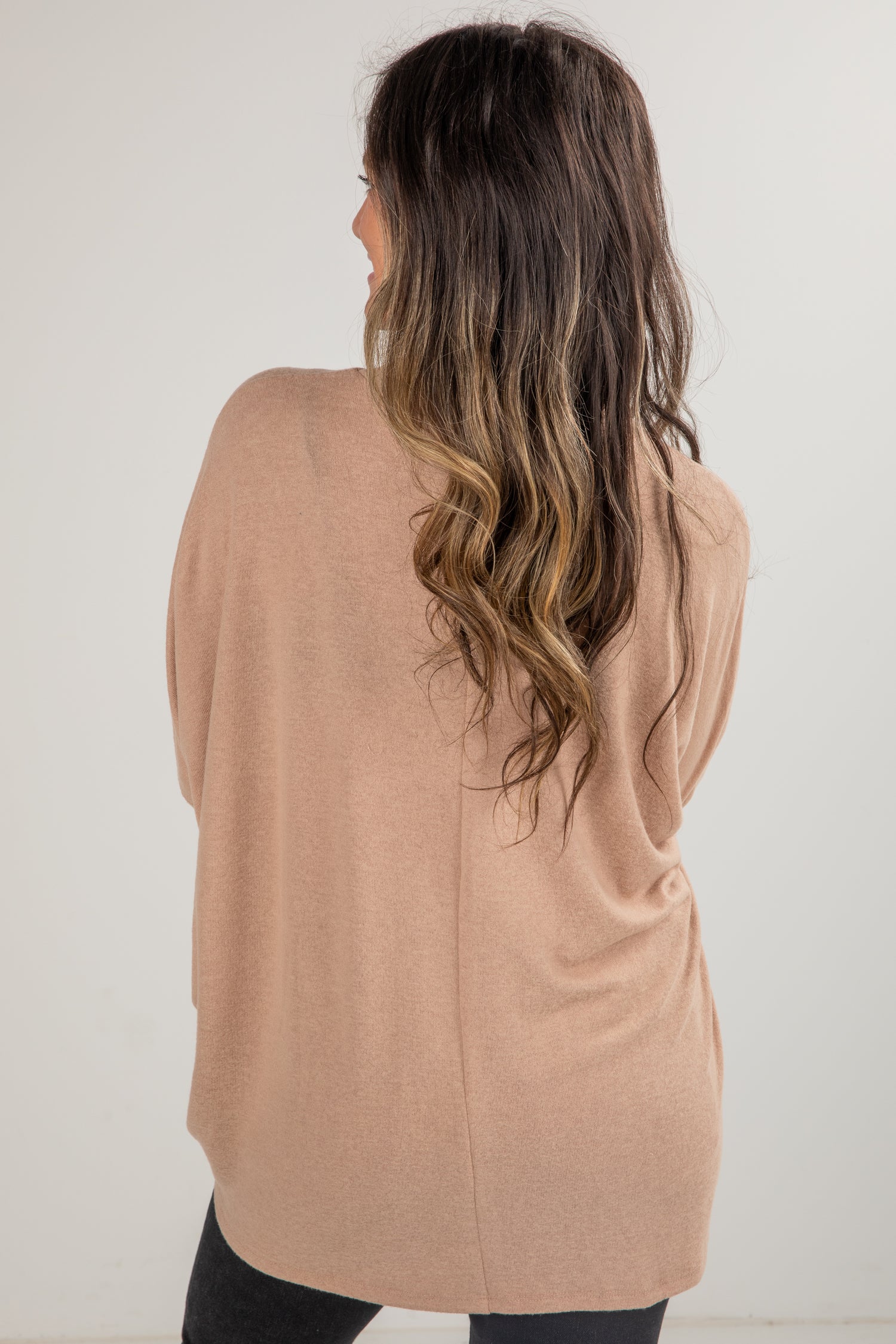 Woman wearing a beige cardigan against a white background