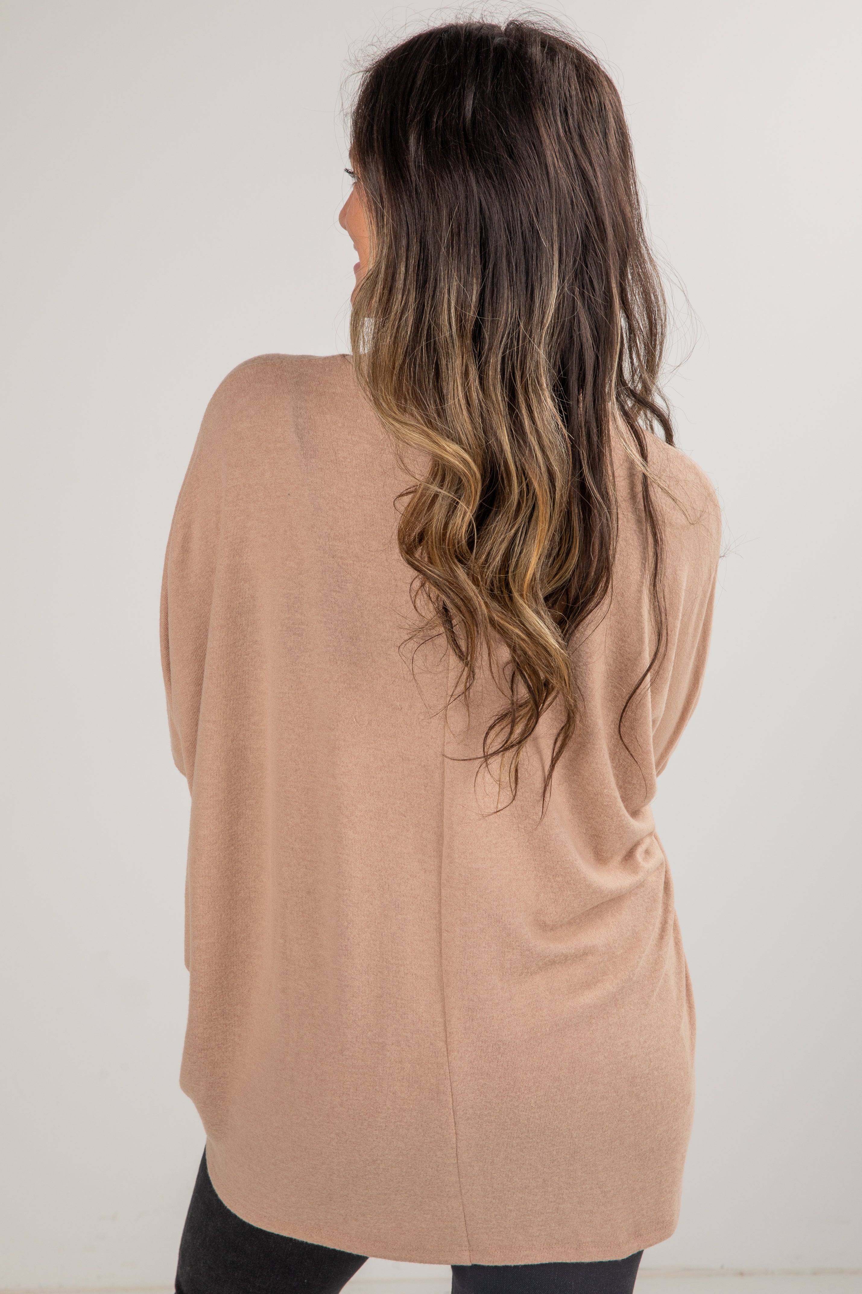 Woman wearing a beige cardigan against a white background