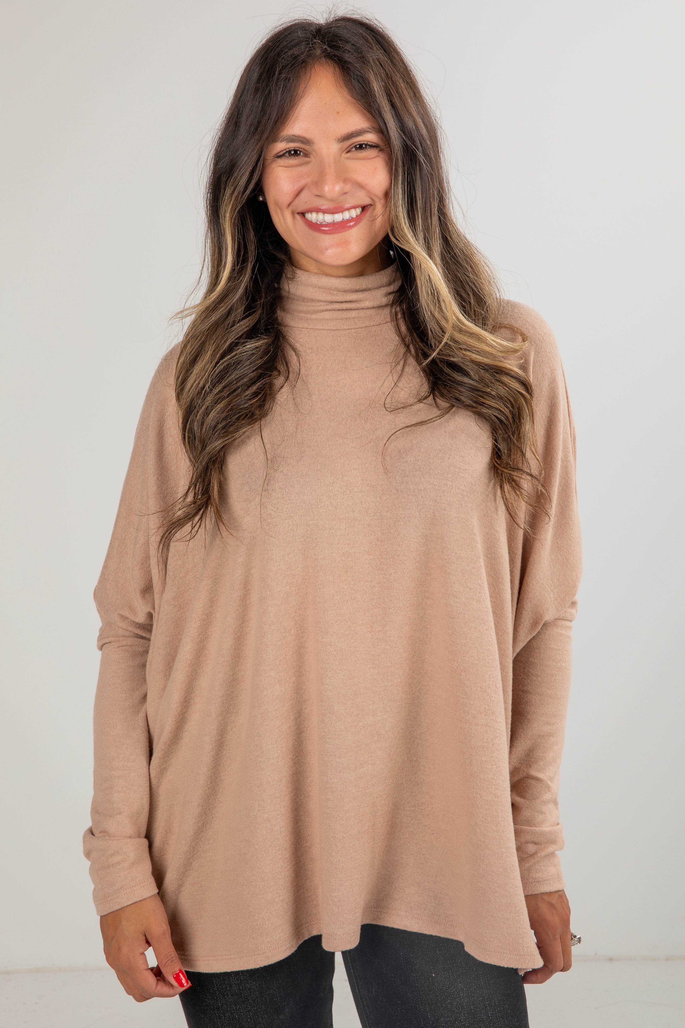 Woman wearing a beige turtleneck sweater against a white background
