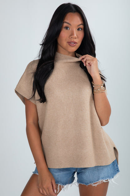 Woman wearing a beige sweater and denim shorts on a white background