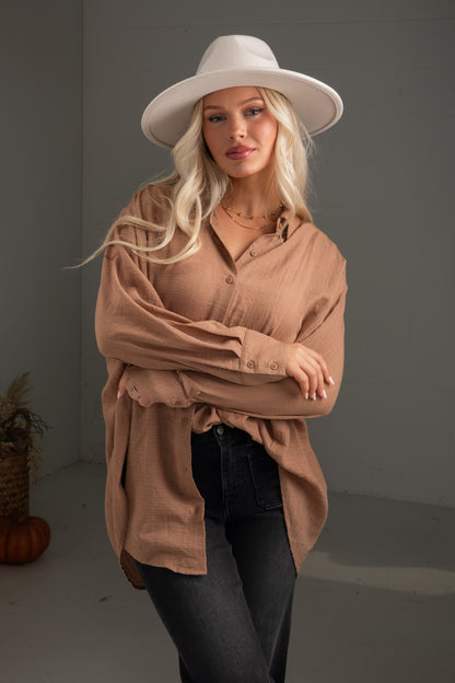 Woman wearing a beige shirt and hat against a gray background