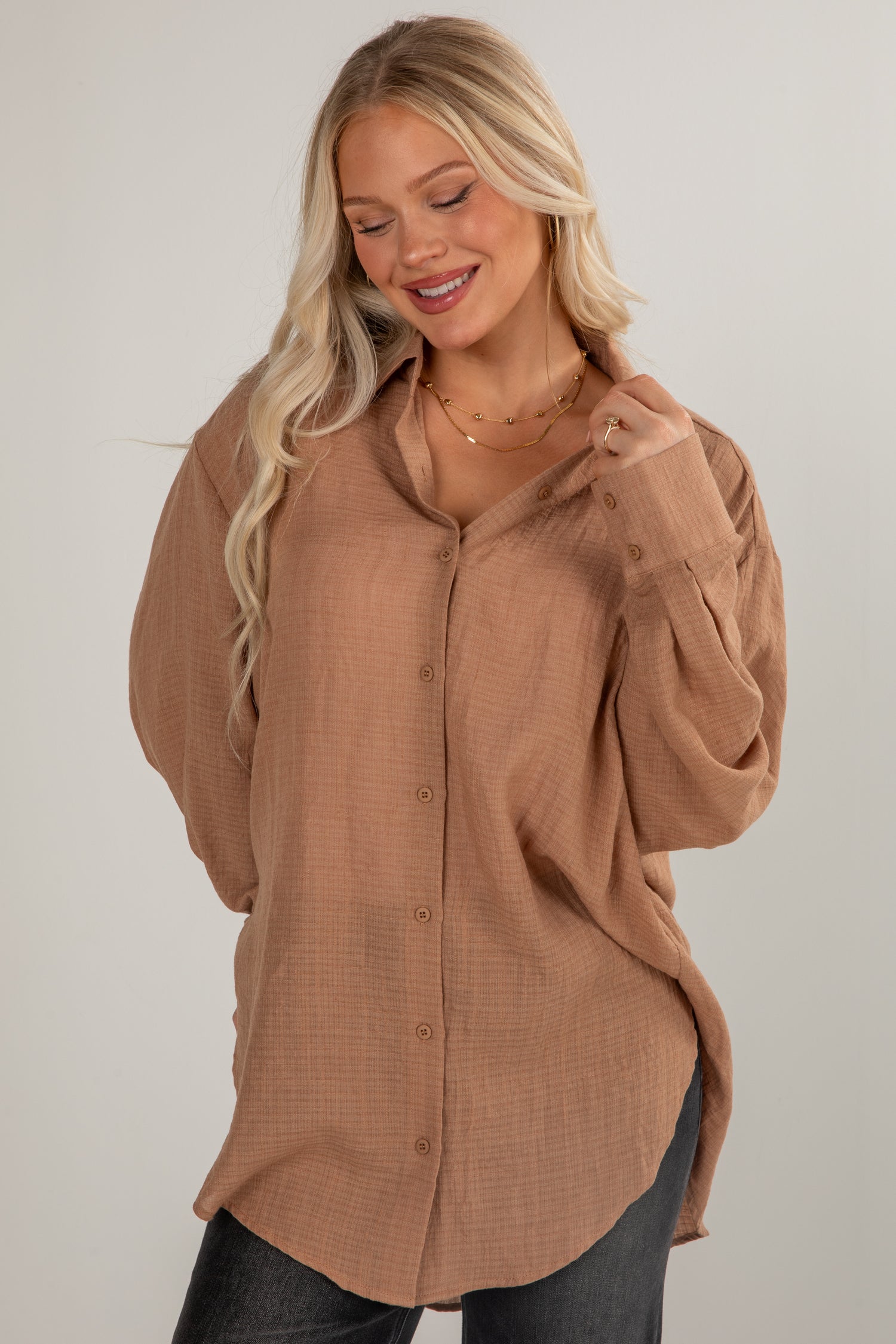Woman wearing a brown button-up shirt against a plain background