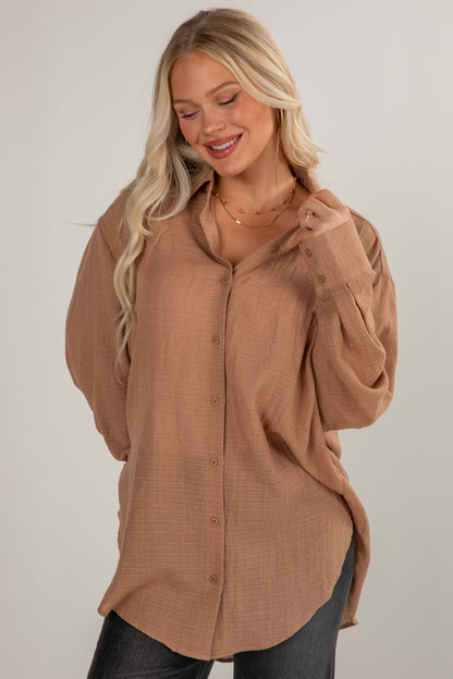 Woman wearing a brown button-up shirt against a plain background