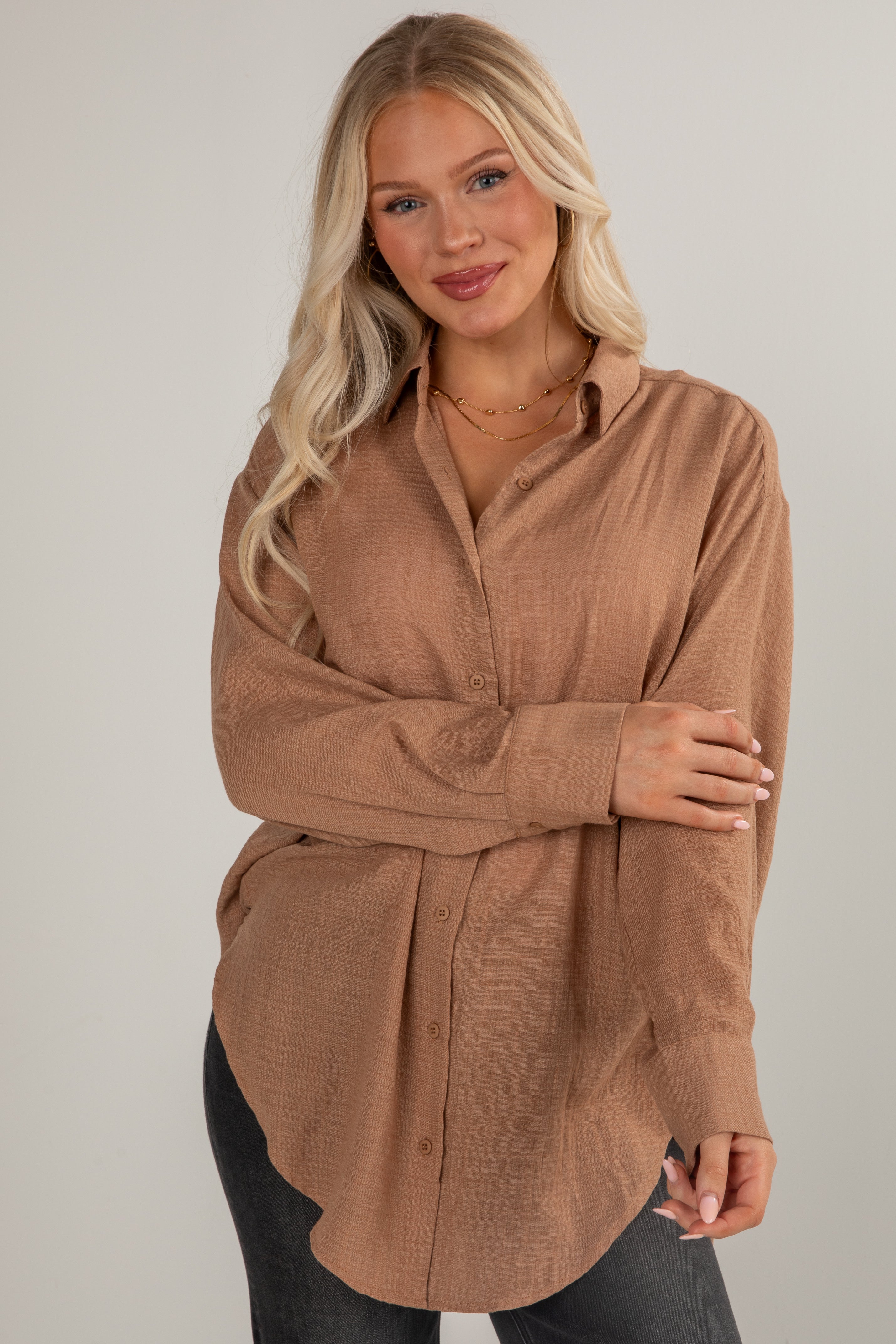 Woman wearing a brown button-up shirt against a plain background