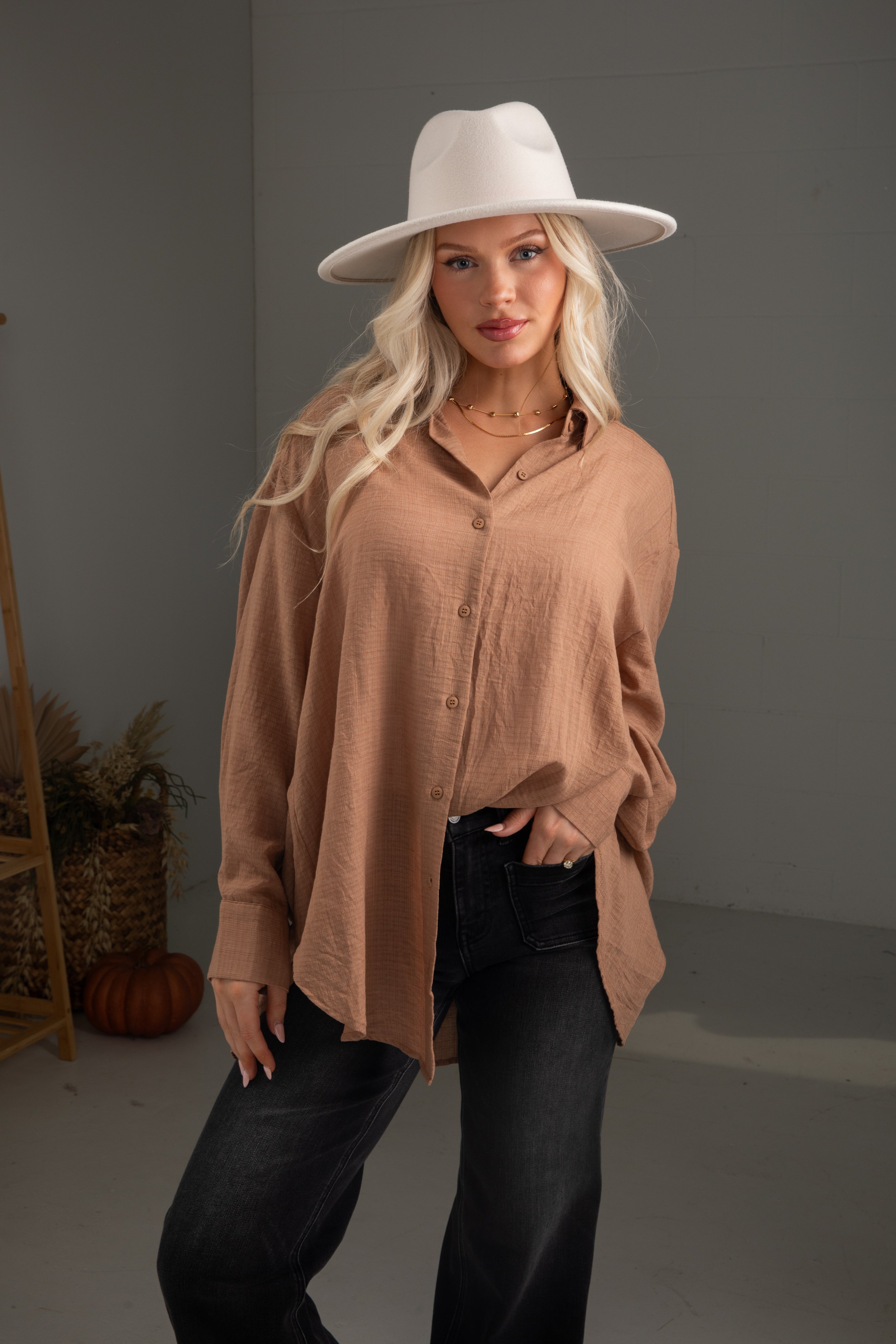 Woman wearing a beige shirt and white hat against a gray background