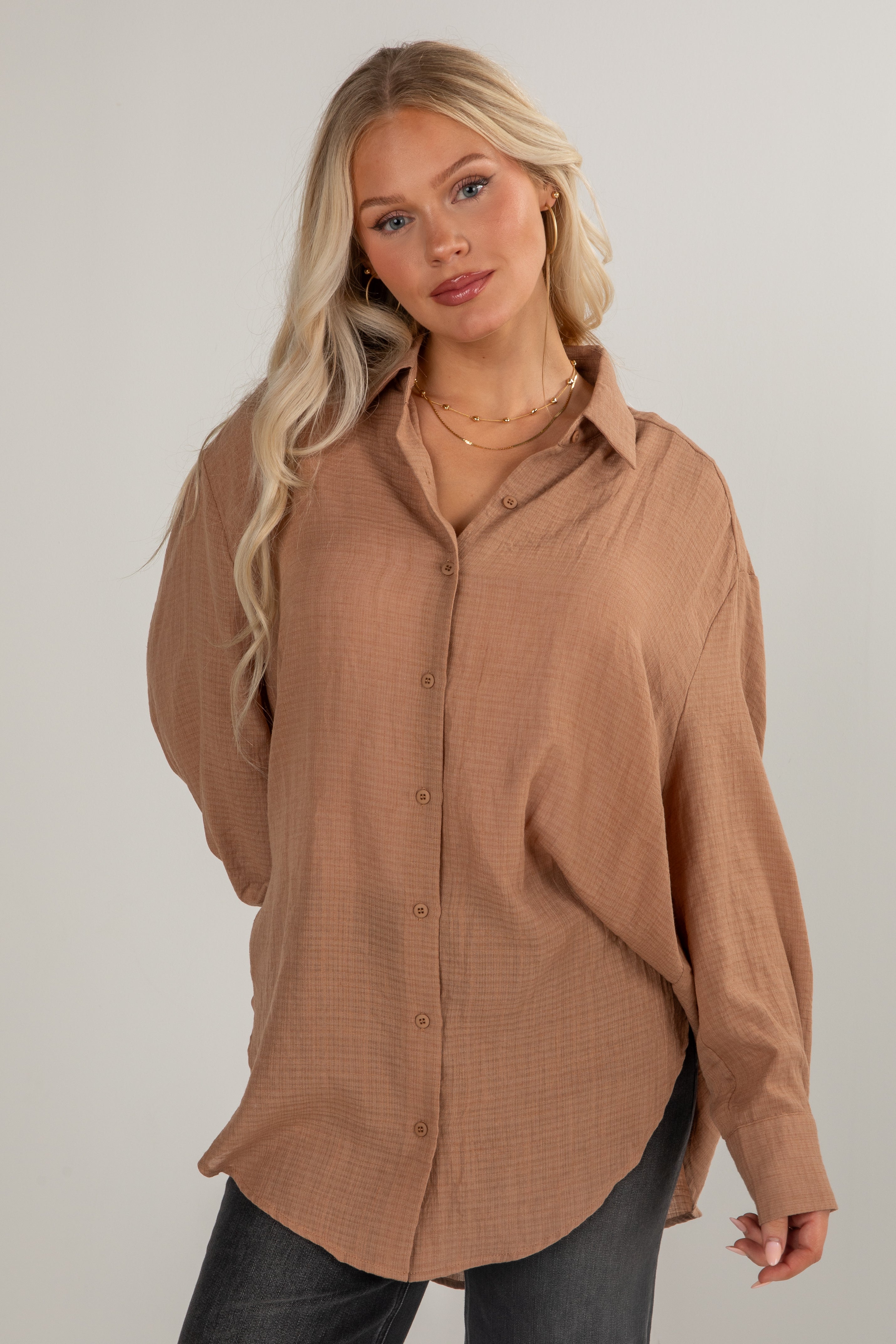 Woman wearing a brown button-up shirt against a plain background