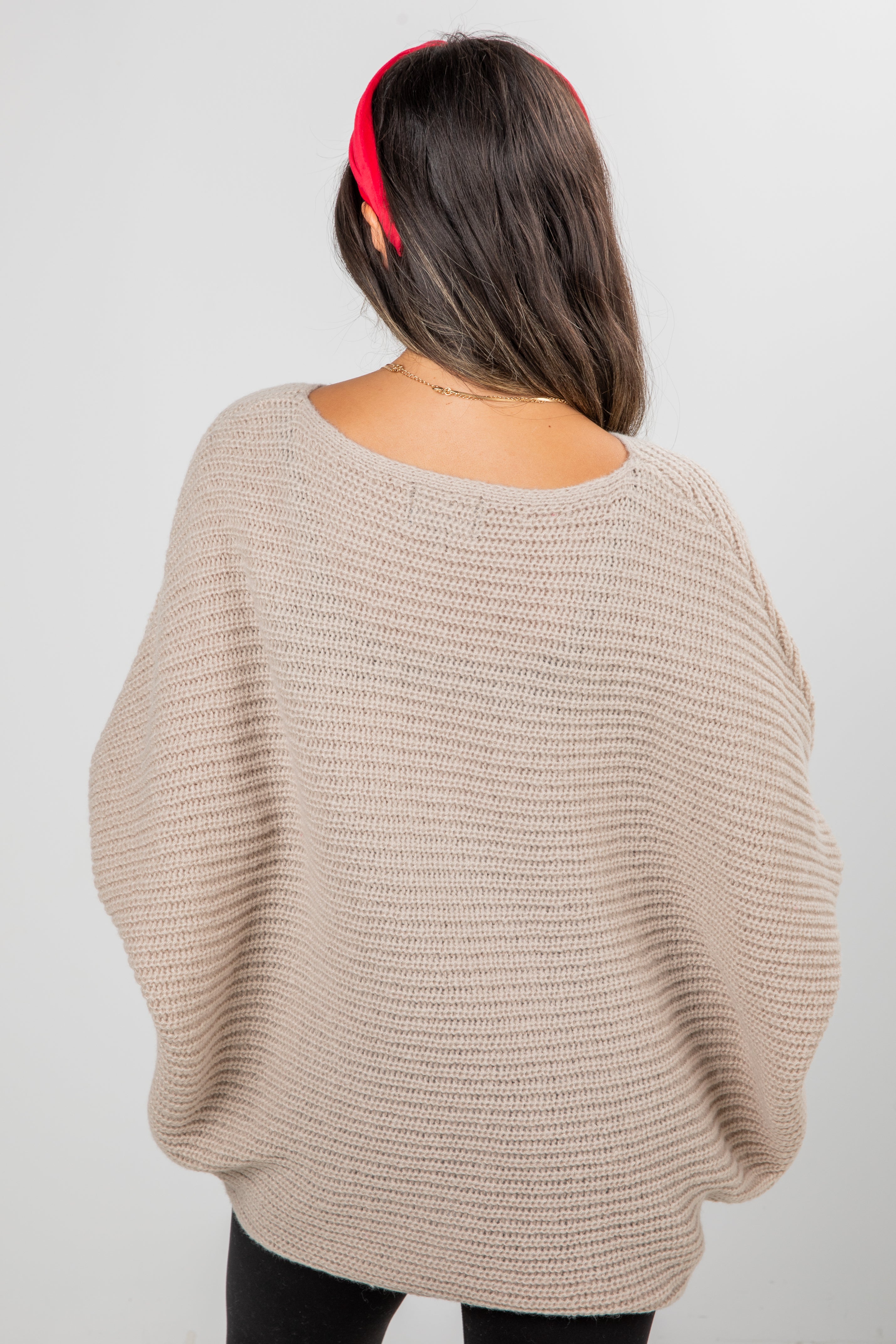 Person wearing a beige sweater with a plain background