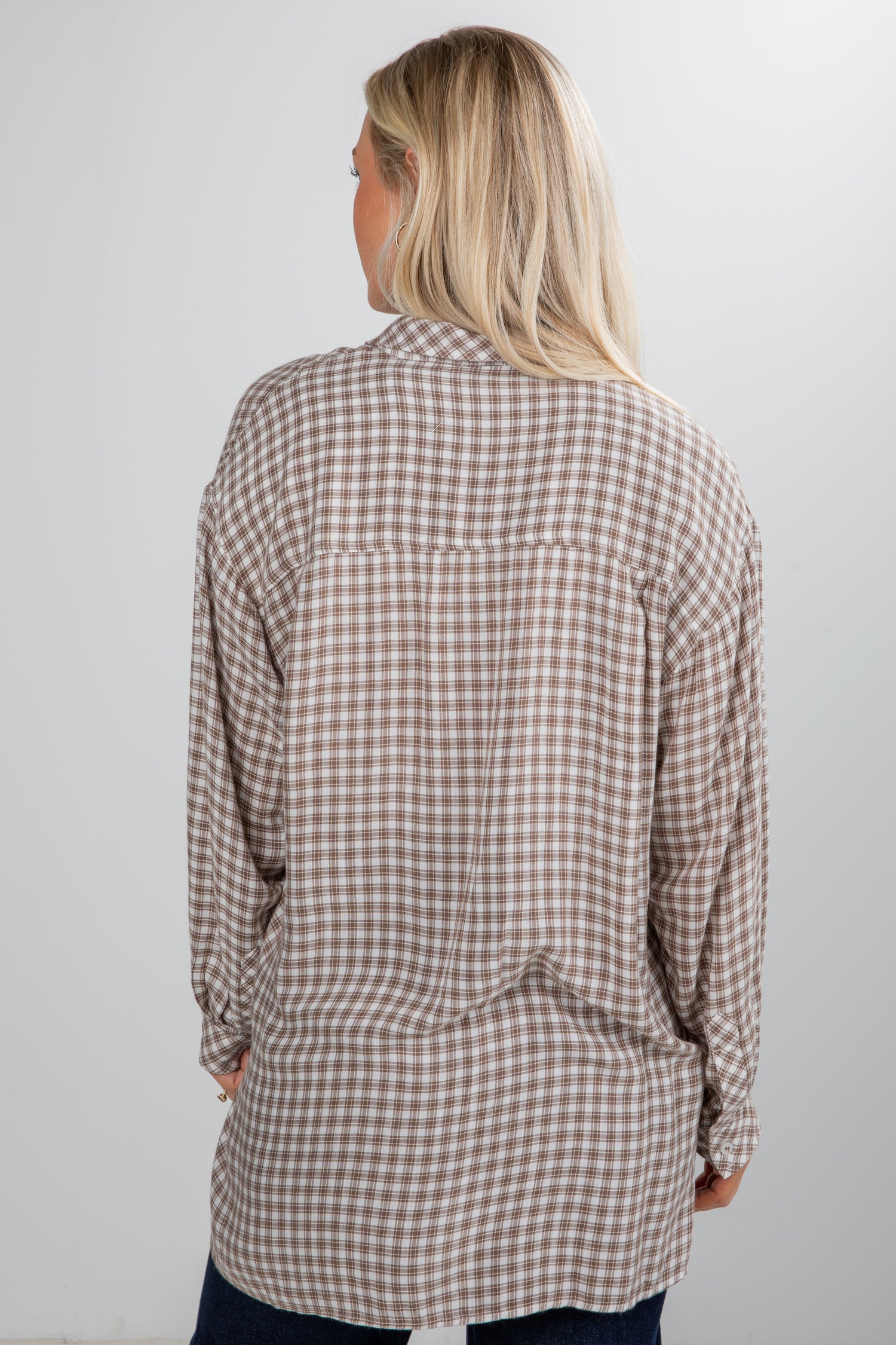 Woman wearing a plaid shirt against a plain background