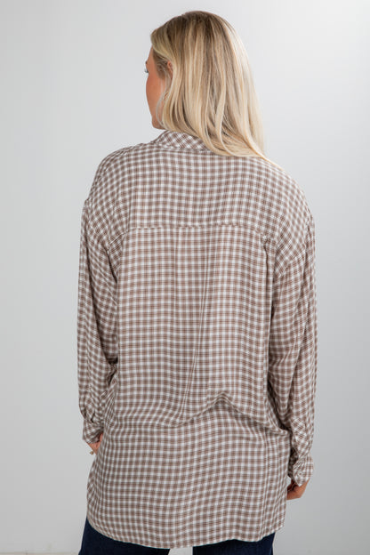 Woman wearing a plaid shirt against a plain background
