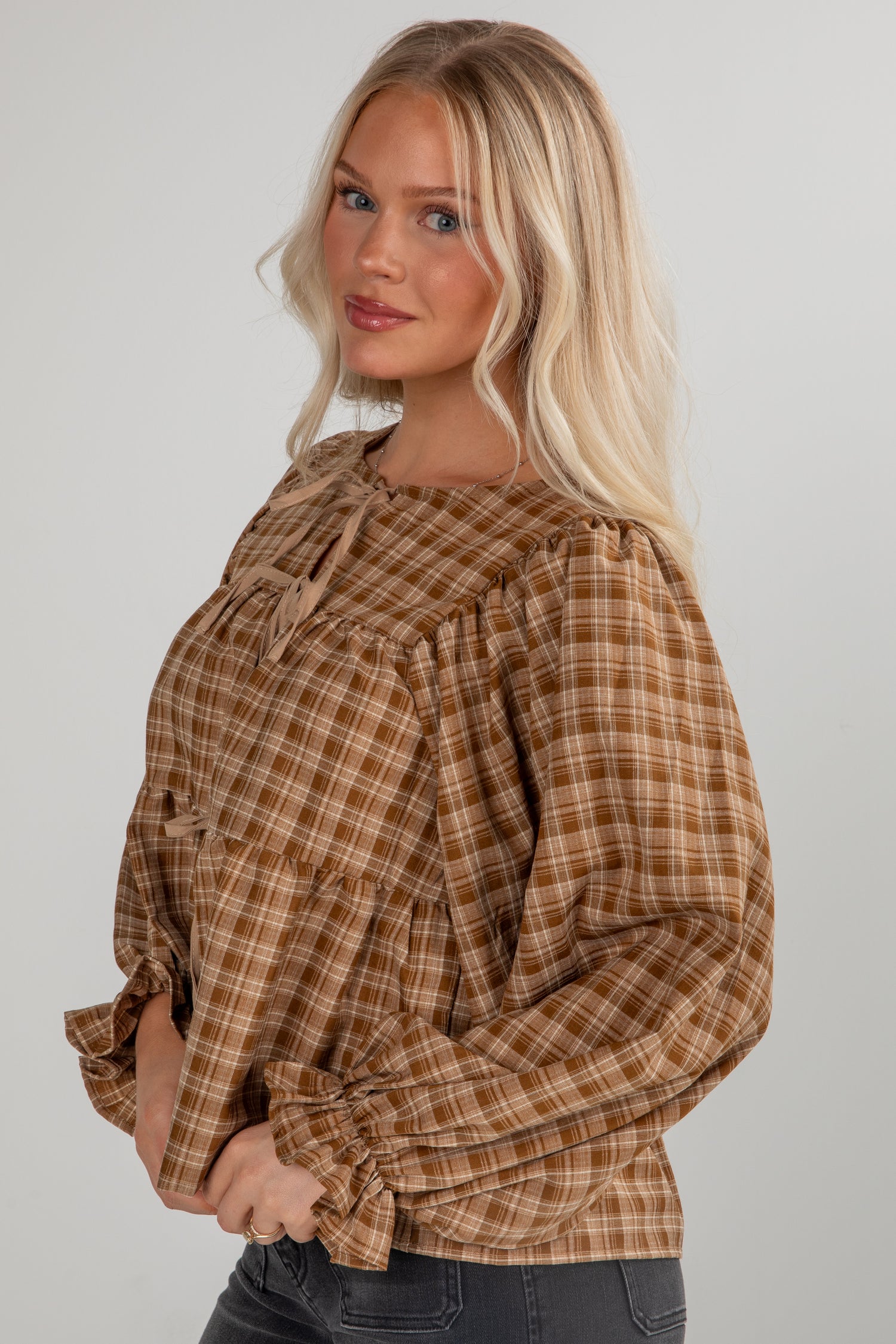 Woman wearing a plaid blouse with long sleeves on a plain background