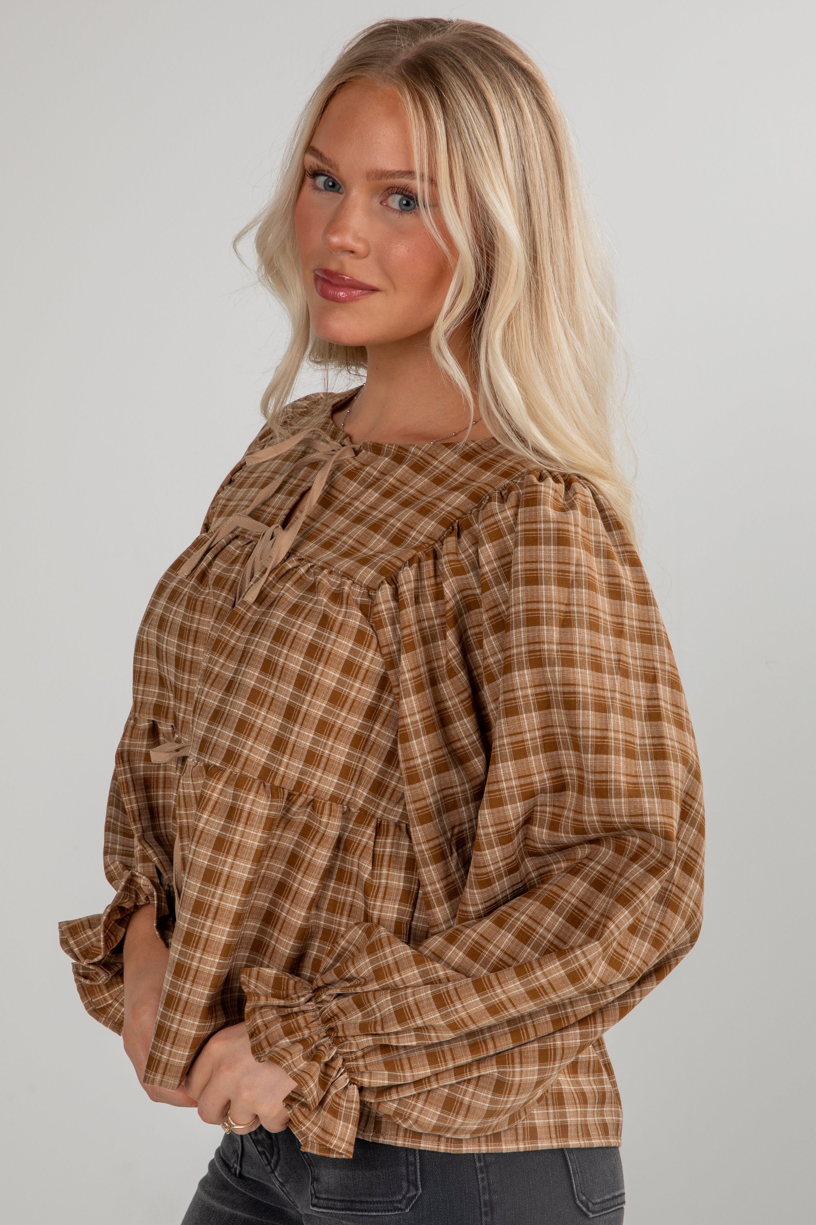 Woman wearing a plaid blouse with long sleeves on a plain background