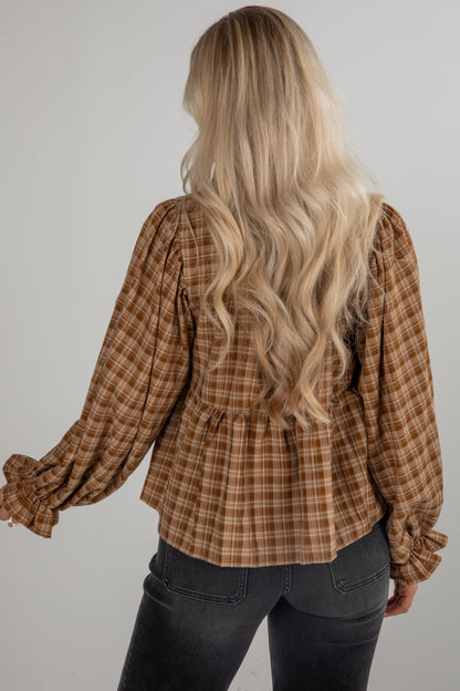 Person wearing a plaid shirt with long blonde hair on a plain background