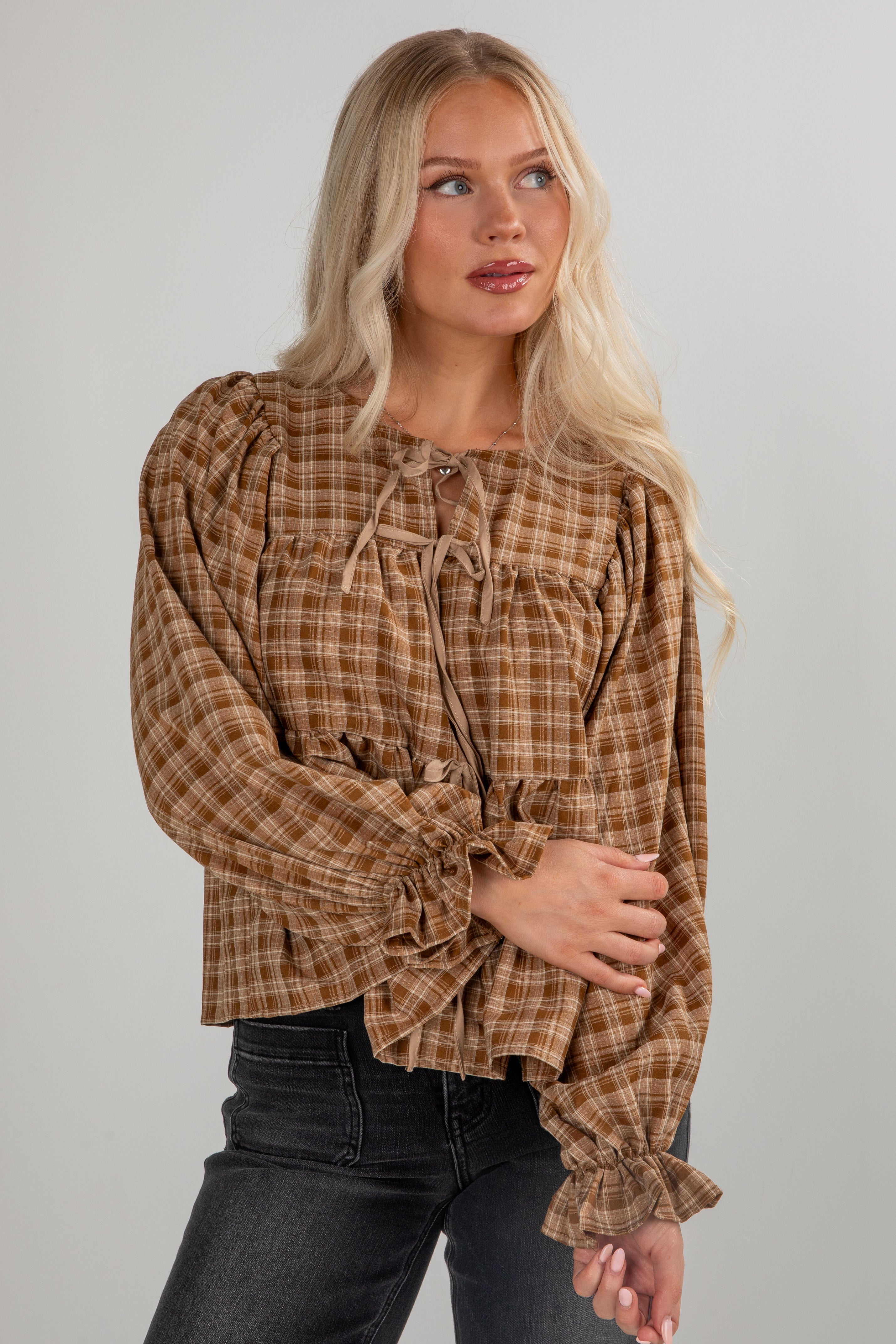 Woman wearing a plaid blouse with long sleeves against a plain background