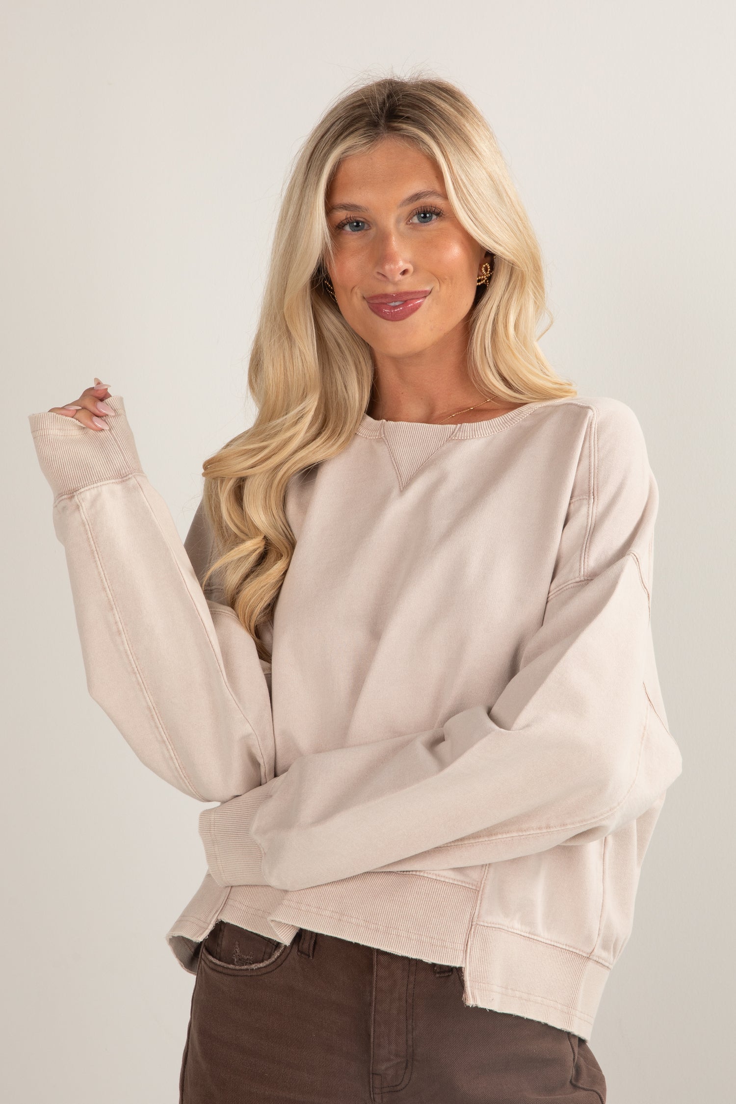 Woman wearing a beige sweater against a plain background