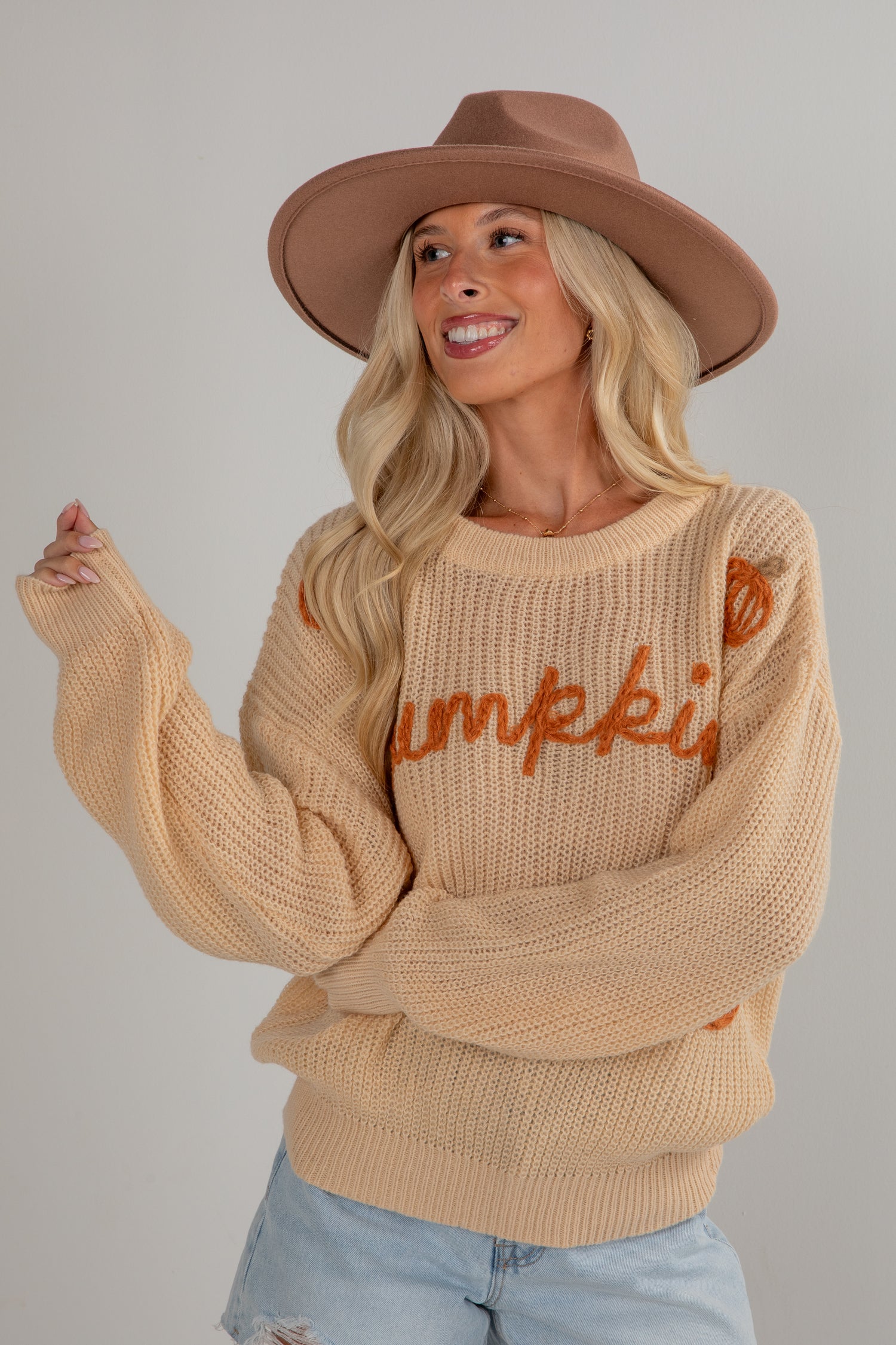 Woman wearing a beige sweater with &