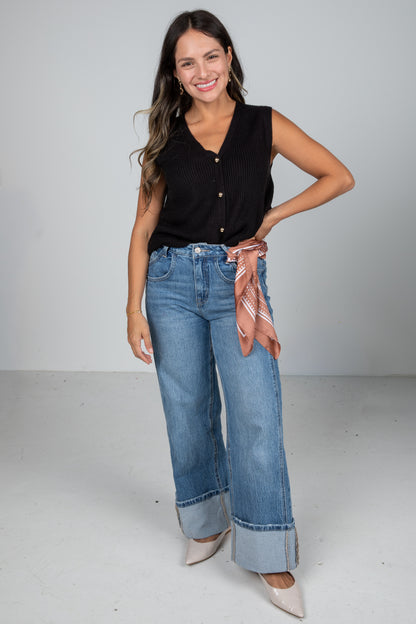 Woman wearing a black top and blue jeans with a white background