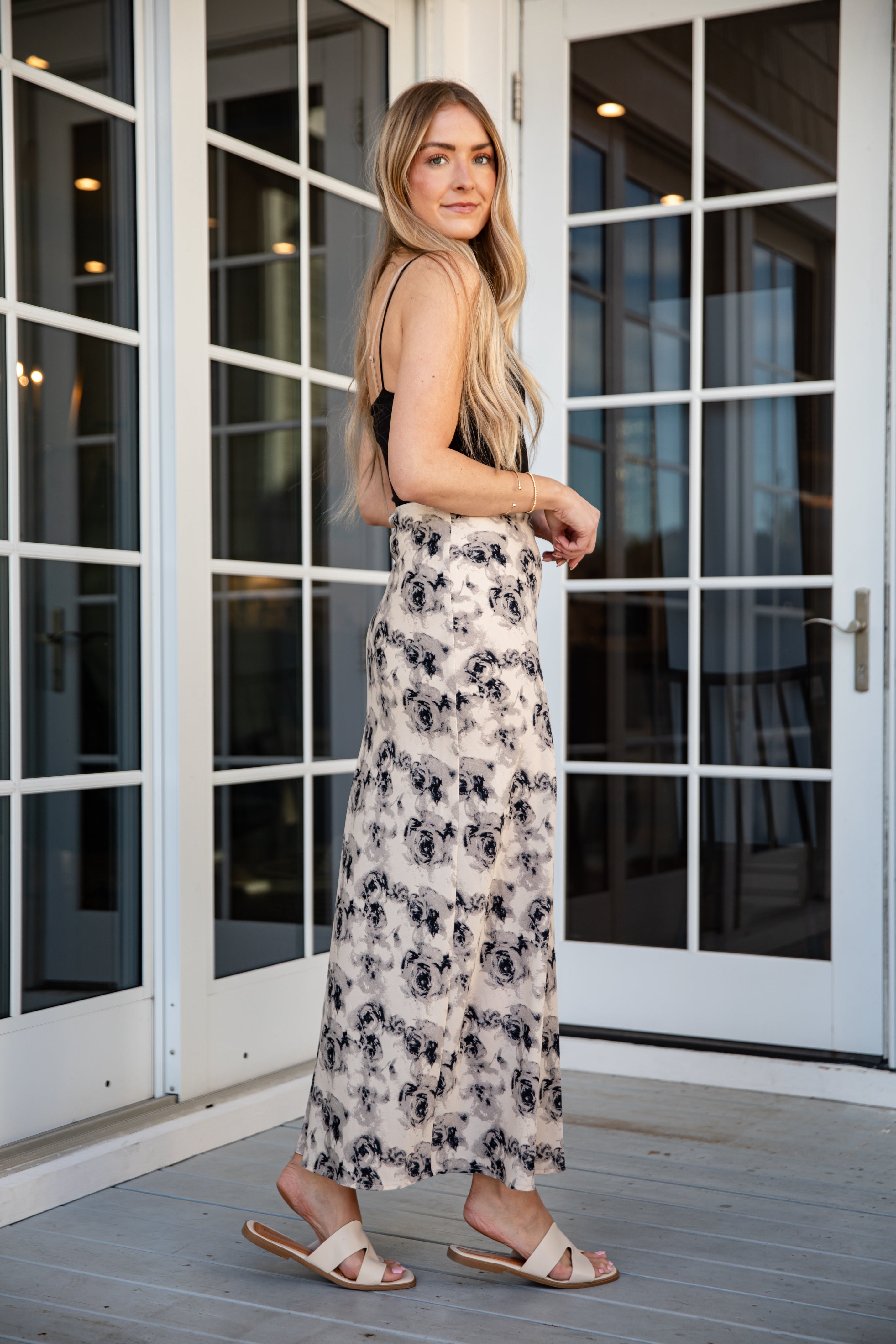Woman in a floral skirt standing in front of glass doors.