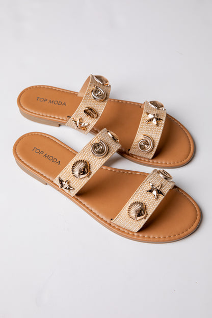 Pair of tan sandals with decorative straps on a light gray background