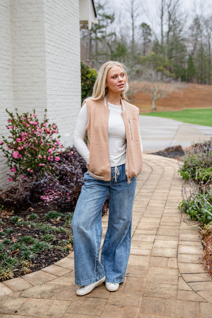 Woman standing on a paved walkway with a garden and house in the background