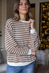 Woman wearing a brown and white striped sweater with a blurred indoor background