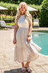 Woman in a white dress standing by a pool with greenery in the background