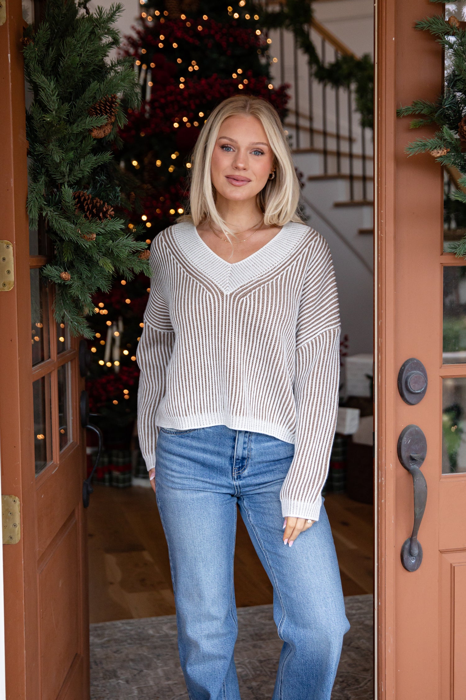 Woman standing in a doorway with a decorated Christmas tree in the background