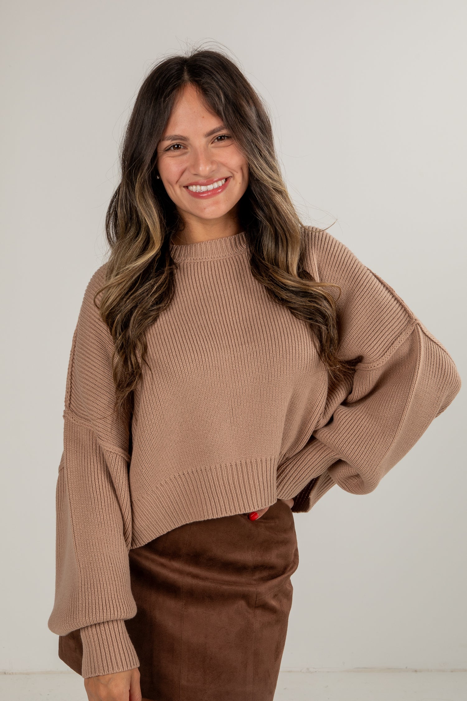 Woman wearing a brown sweater and pants against a white background