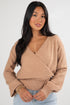 Woman wearing a beige wrap sweater against a white background