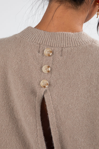 Close-up of a brown sweater with button details on a neutral background