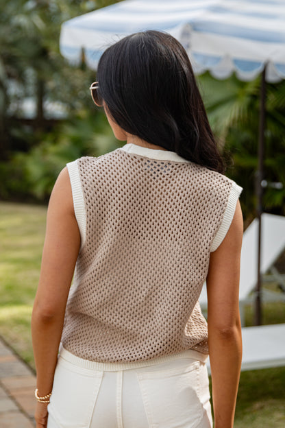 Woman wearing a beige mesh top and white pants outdoors