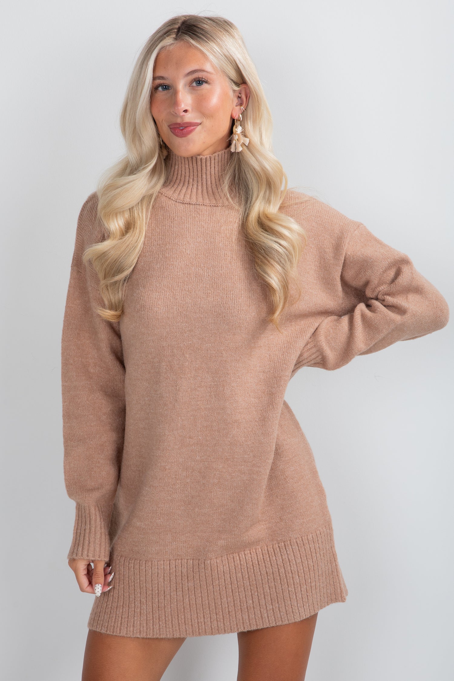 Woman wearing a brown sweater dress against a white background