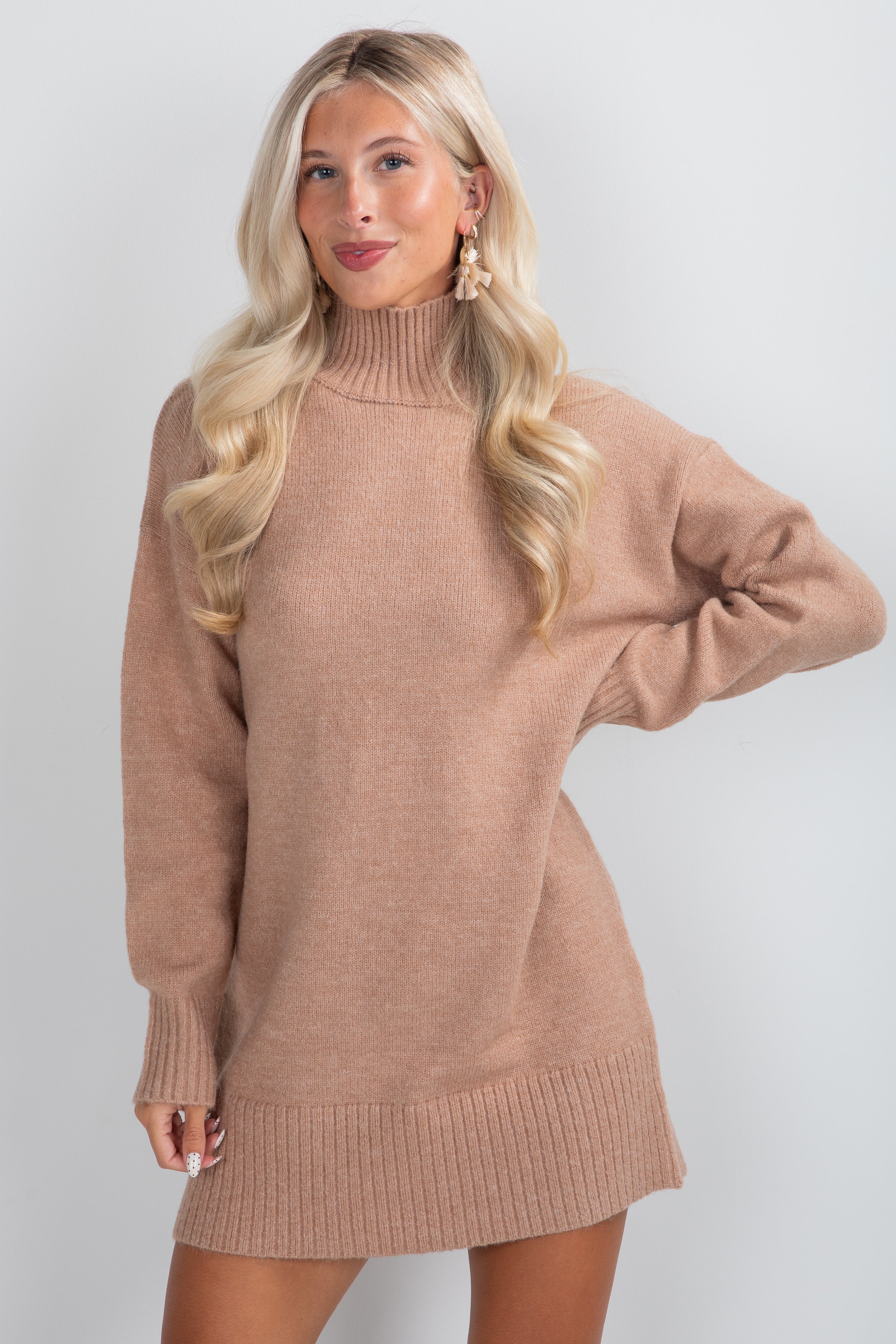 Woman wearing a brown sweater dress against a white background