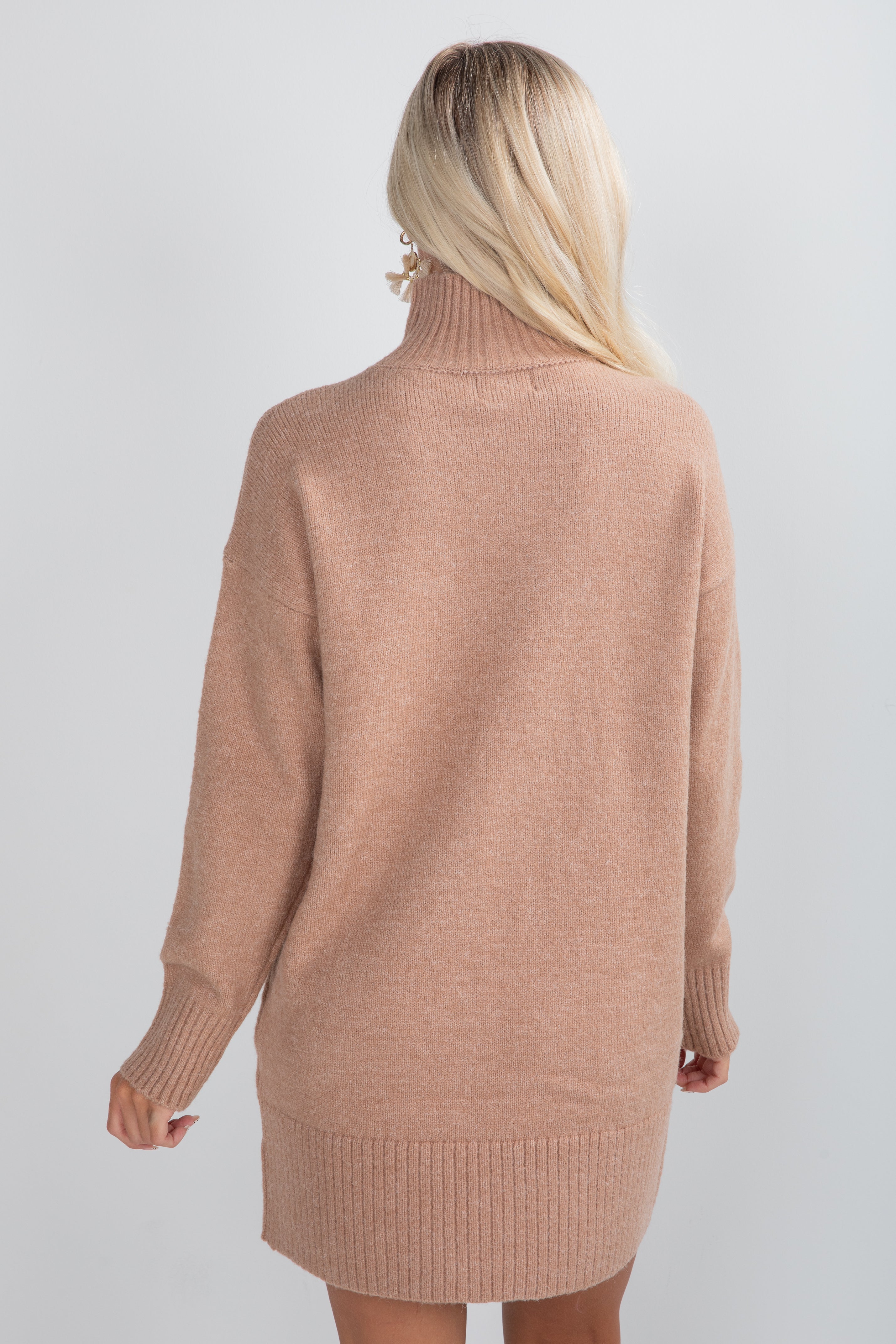 Person wearing a beige sweater dress against a white background