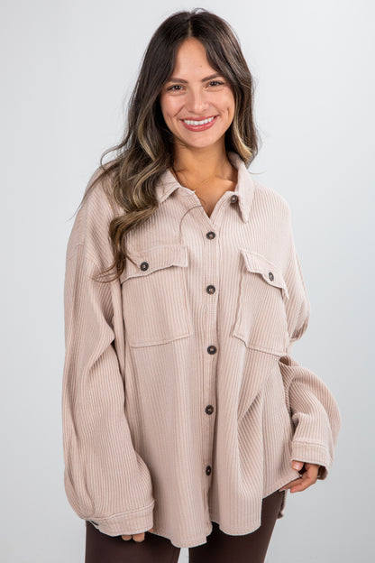 Woman wearing a beige corduroy shirt with black buttons on a white background