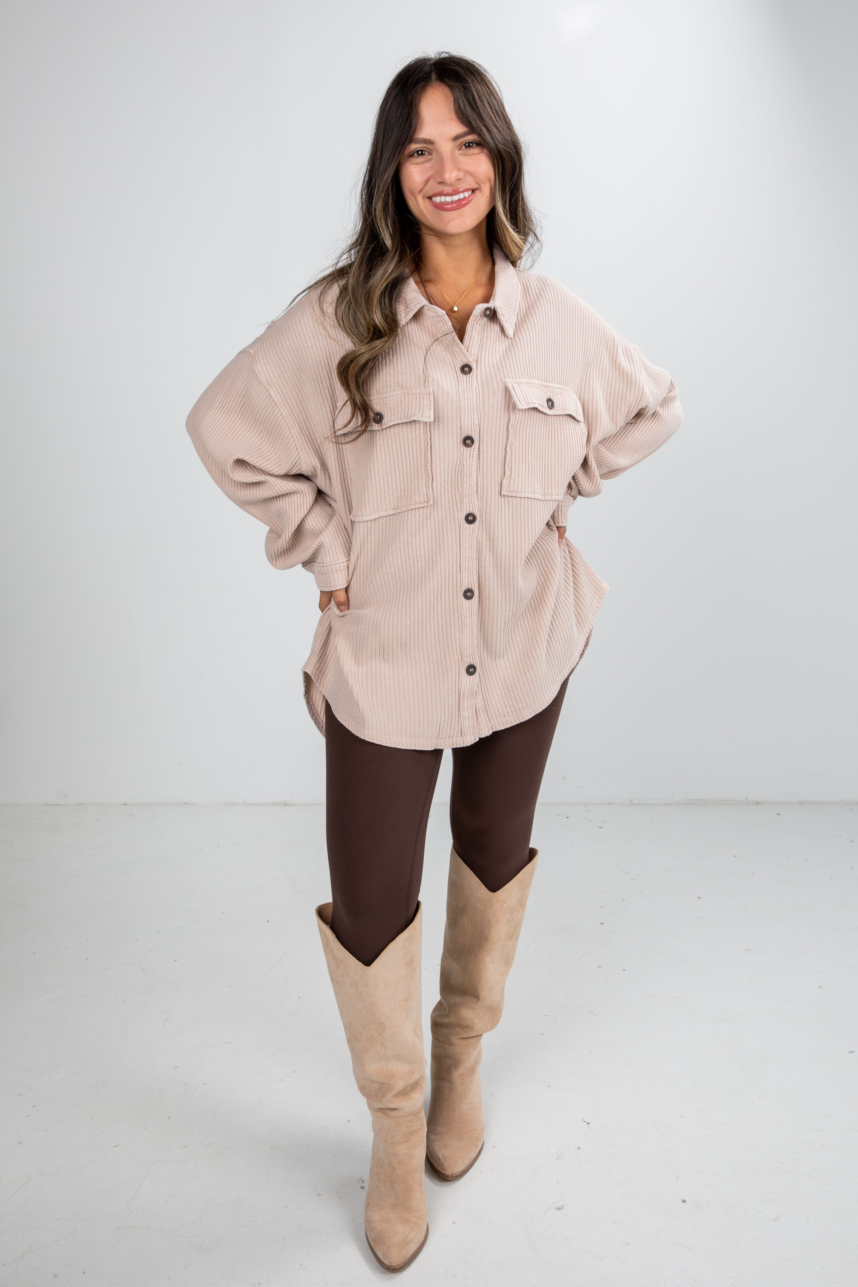 Woman wearing a beige shirt, brown pants, and tan boots on a white background