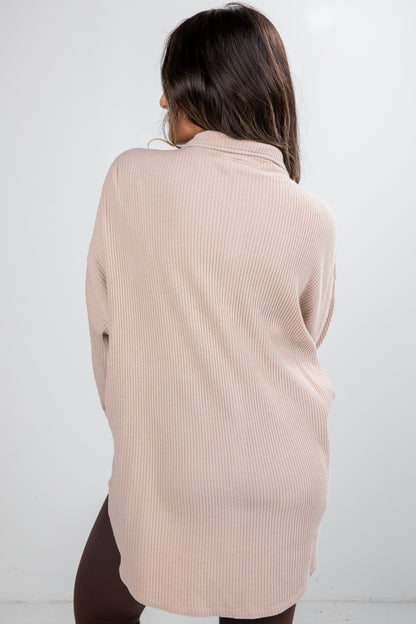 Woman wearing a beige ribbed sweater against a white background