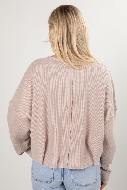 Person wearing a beige ribbed sweater and light blue jeans against a white background