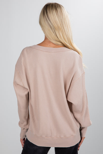 Beige ribbed sweater worn by a person on a plain background