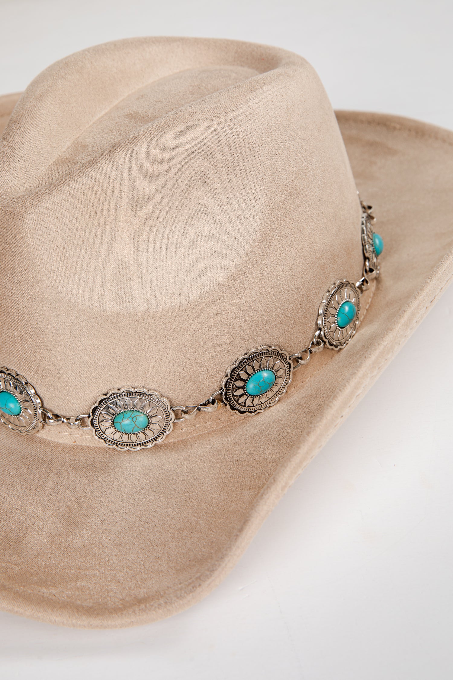 Beige cowboy hat with turquoise stone and silver band on a white background