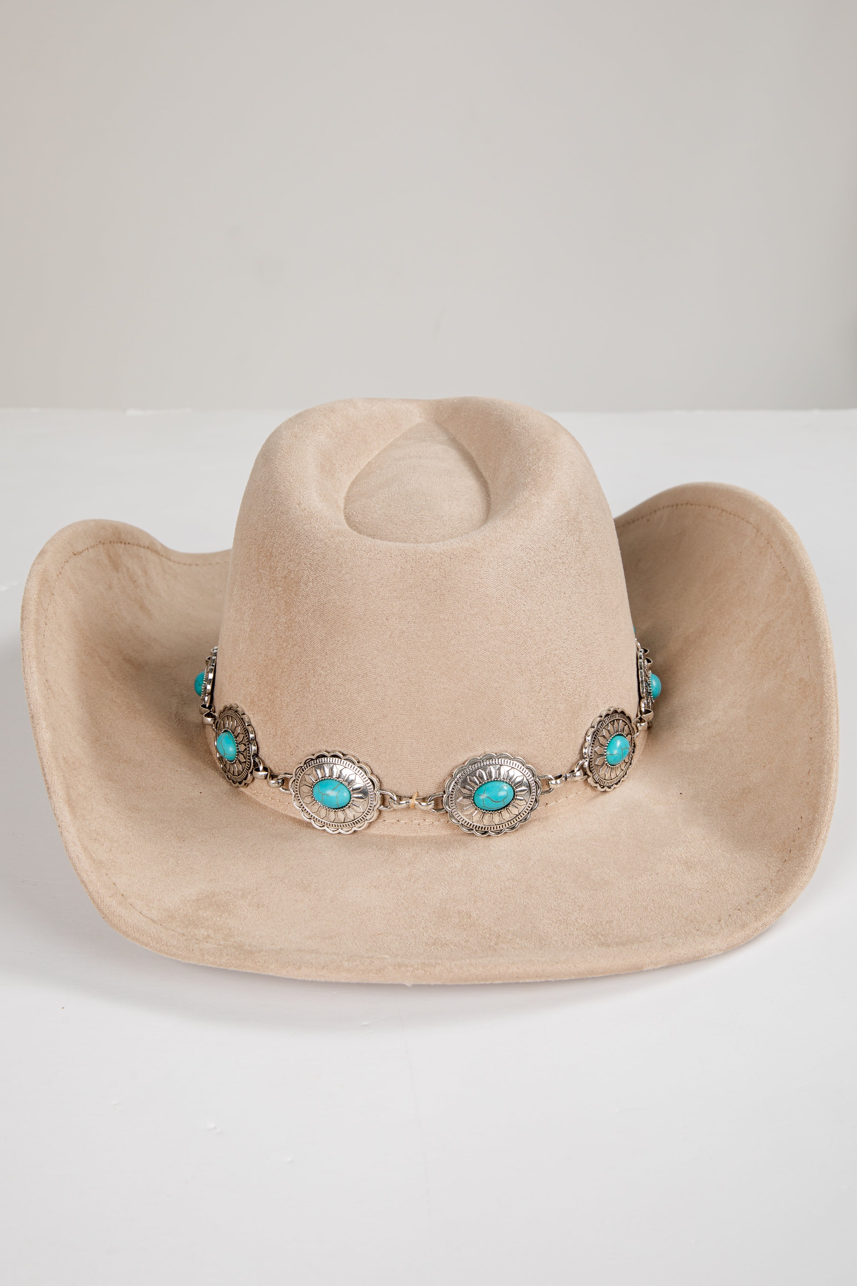 Beige cowboy hat with turquoise and silver embellishments on a white background