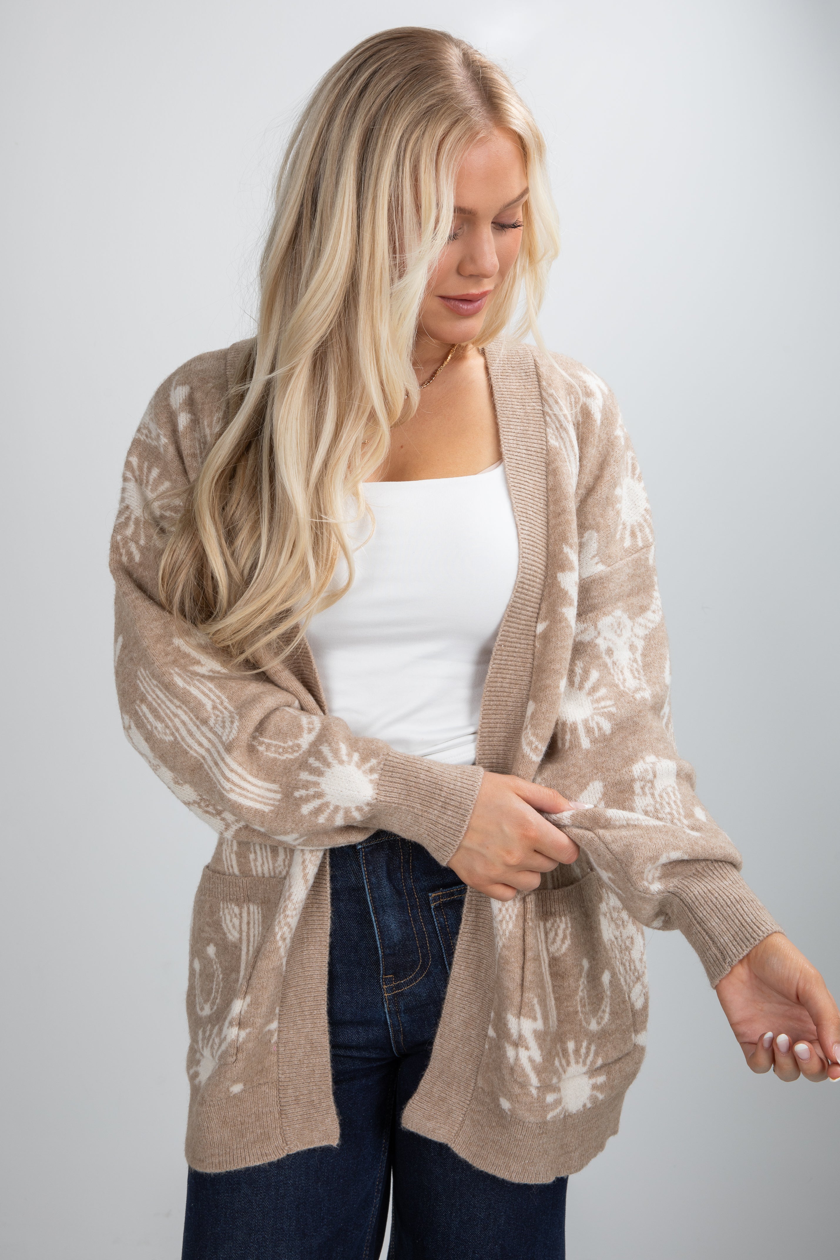 Woman wearing a beige cardigan with a white pattern on a plain background